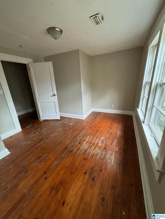 spare room with dark hardwood / wood-style floors and a textured ceiling