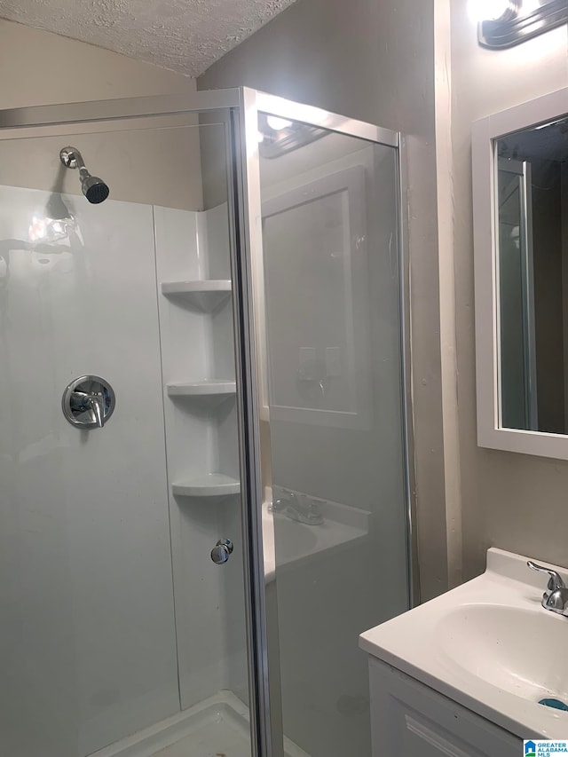 bathroom with an enclosed shower, vanity, and a textured ceiling