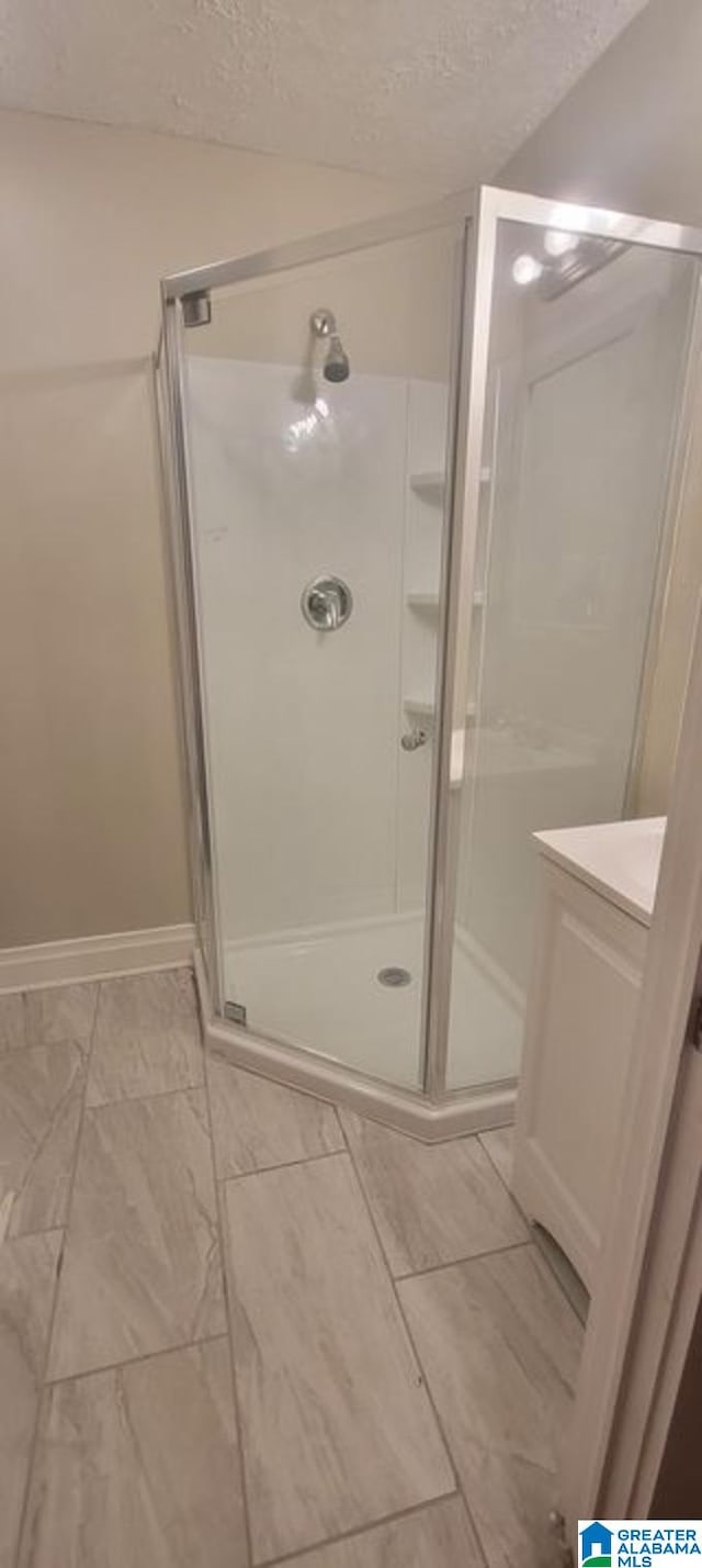 bathroom with a shower with shower door and a textured ceiling