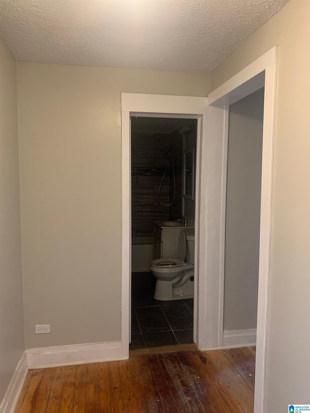 hallway featuring a sink, a textured ceiling, and hardwood / wood-style flooring