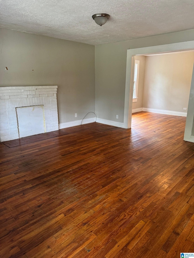 unfurnished room featuring dark wood-type flooring, a fireplace, and a textured ceiling