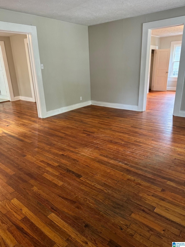 unfurnished room with dark wood-type flooring and a textured ceiling