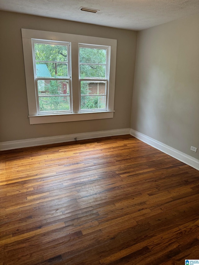 empty room featuring dark hardwood / wood-style floors and a textured ceiling