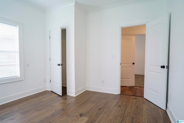 unfurnished bedroom featuring crown molding and dark hardwood / wood-style floors