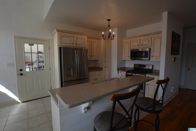 kitchen with appliances with stainless steel finishes, decorative light fixtures, sink, a chandelier, and a center island with sink