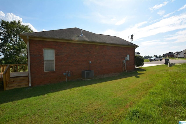 view of side of property with a wooden deck, a yard, and central air condition unit