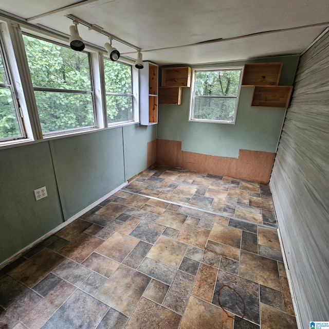 interior space featuring a wealth of natural light, rail lighting, and dark tile patterned flooring