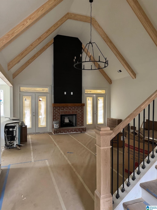 unfurnished living room with french doors, beamed ceiling, and stairway