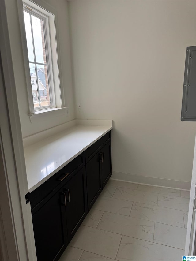 bathroom with marble finish floor, electric panel, and baseboards