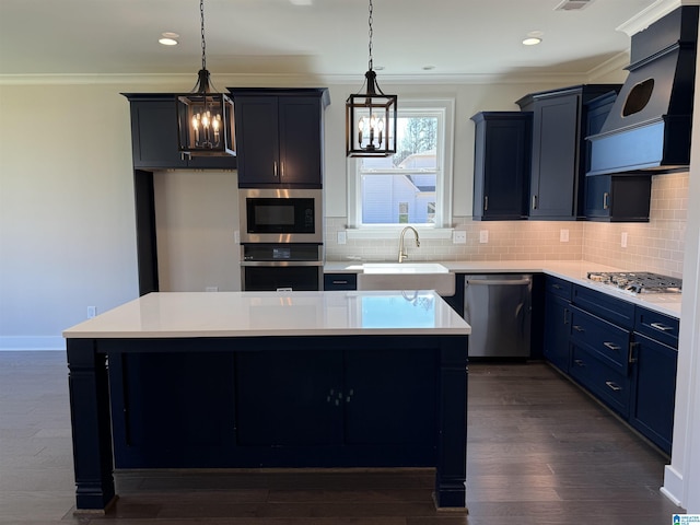 kitchen with hanging light fixtures, a kitchen island, appliances with stainless steel finishes, and light countertops