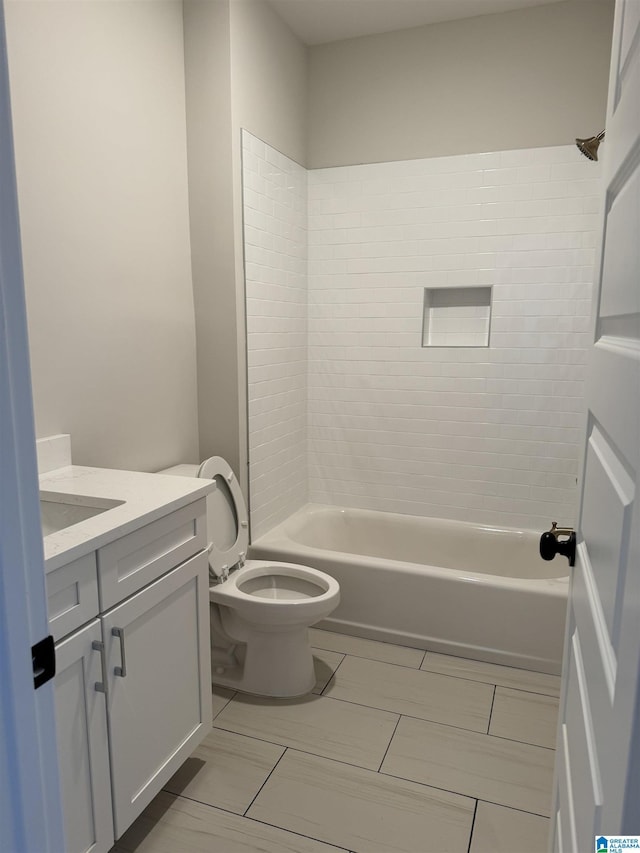 full bathroom featuring vanity, tiled shower / bath, and toilet