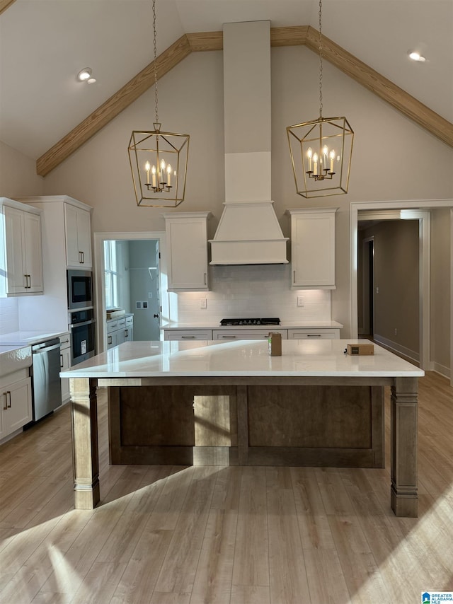 kitchen featuring pendant lighting, decorative backsplash, custom exhaust hood, and appliances with stainless steel finishes