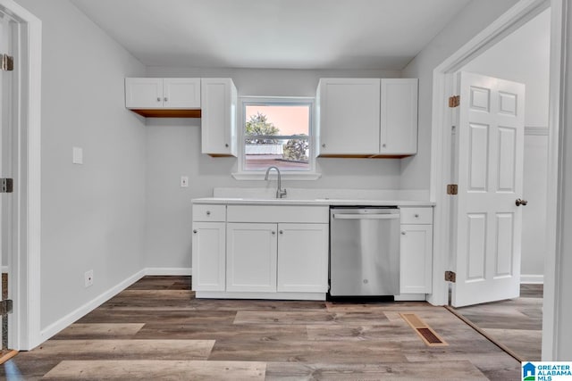 kitchen featuring sink, stainless steel dishwasher, white cabinetry, and light hardwood / wood-style flooring