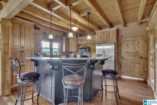 kitchen featuring stainless steel fridge, hanging light fixtures, a center island, beamed ceiling, and light brown cabinets