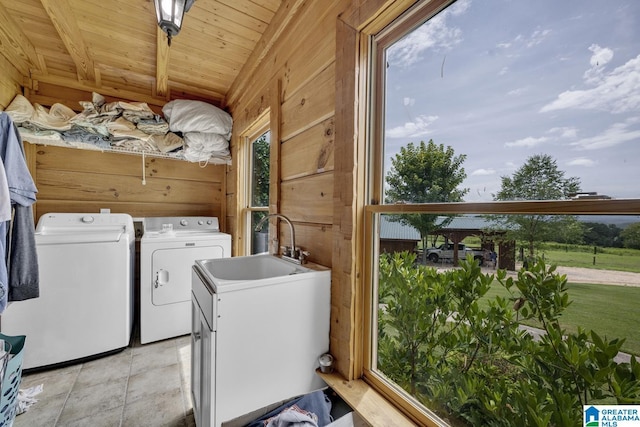 washroom with wood ceiling, washing machine and clothes dryer, wooden walls, and a wealth of natural light