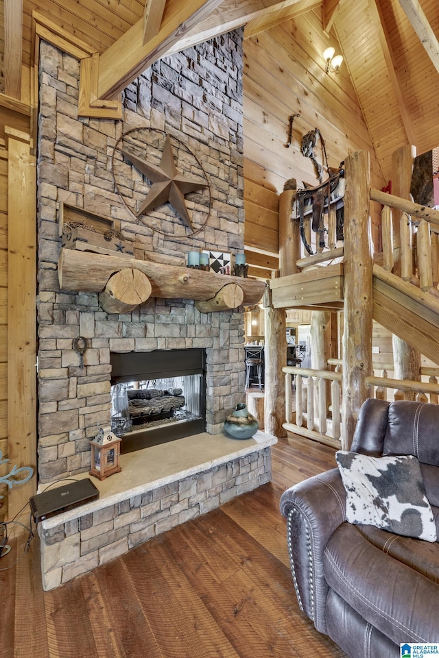 living room featuring hardwood / wood-style floors, high vaulted ceiling, a fireplace, beamed ceiling, and wood walls