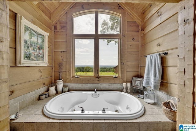 bathroom with vaulted ceiling, tiled bath, wooden ceiling, and wooden walls