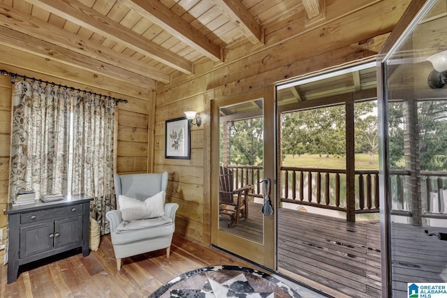 living area with beamed ceiling, wooden walls, hardwood / wood-style flooring, and wooden ceiling