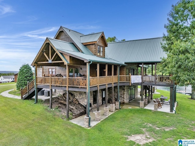 rear view of house with a wooden deck, a lawn, and a patio