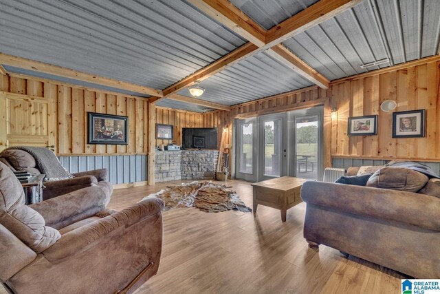 living room with beamed ceiling, wooden walls, light wood-type flooring, and french doors