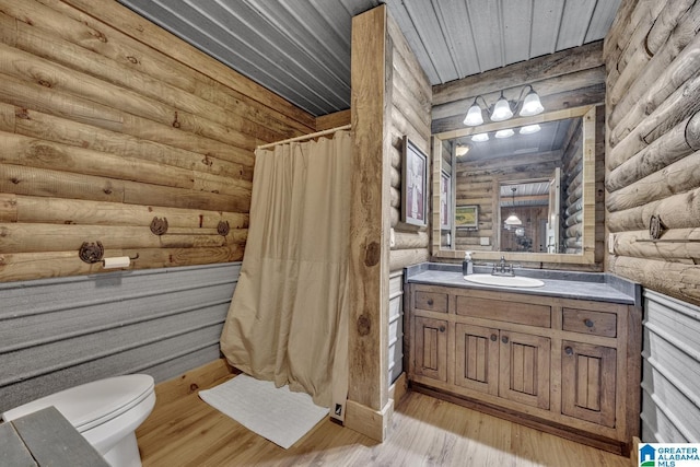 bathroom featuring rustic walls, hardwood / wood-style flooring, vanity, toilet, and a shower with shower curtain