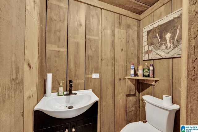 bathroom with wood ceiling, vanity, toilet, and wood walls