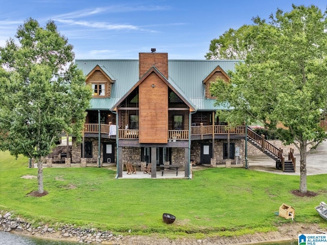 rear view of property featuring a patio, a deck, and a lawn