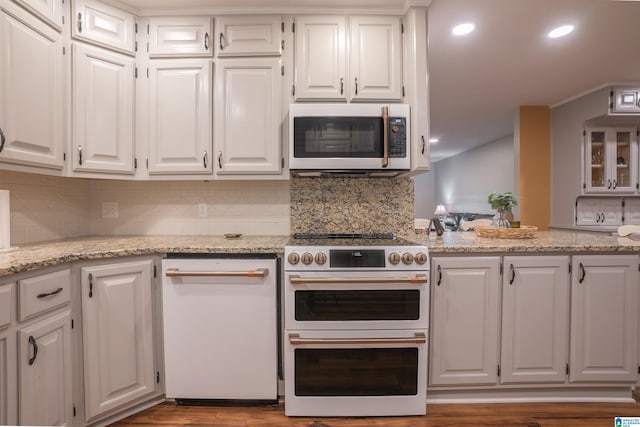 kitchen with light stone counters, tasteful backsplash, range with two ovens, and white cabinets