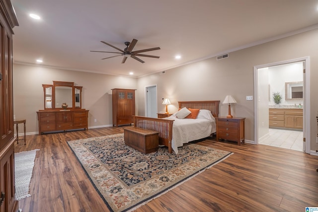 bedroom featuring crown molding, dark wood-type flooring, ceiling fan, and ensuite bathroom