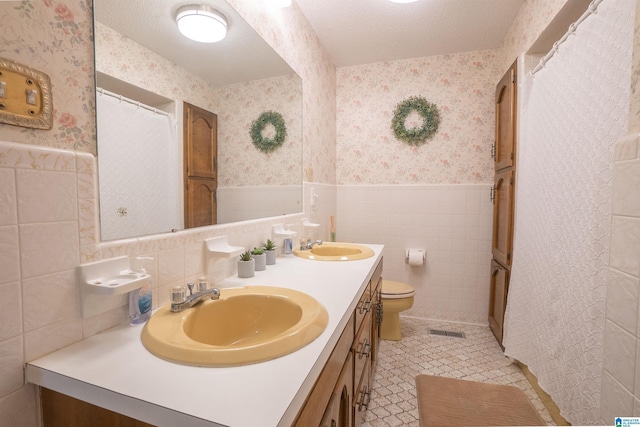 bathroom featuring vanity, tile walls, a textured ceiling, and toilet