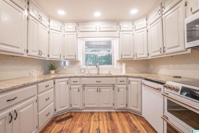 kitchen with white appliances, sink, light wood-type flooring, and white cabinets