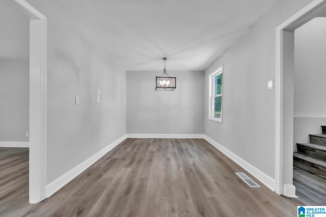 unfurnished dining area featuring wood-type flooring and a notable chandelier