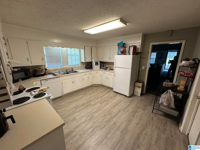 kitchen featuring white cabinets, plenty of natural light, white appliances, light hardwood / wood-style floors, and a textured ceiling