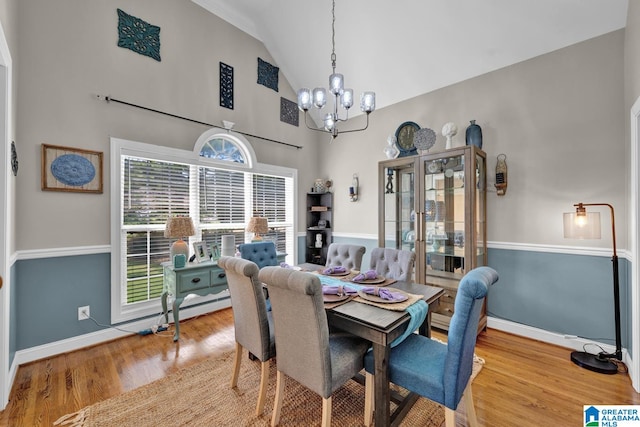 dining space featuring light hardwood / wood-style flooring, high vaulted ceiling, a notable chandelier, and a wealth of natural light