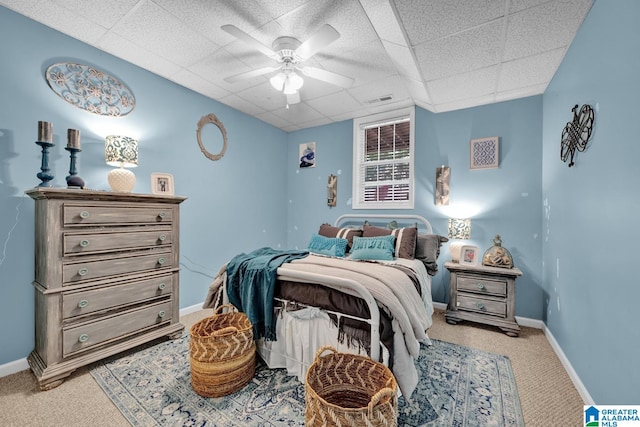 carpeted bedroom with a paneled ceiling and ceiling fan