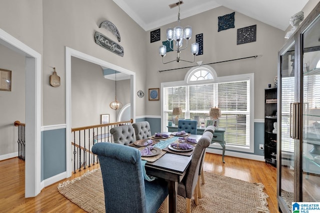 dining area with light hardwood / wood-style flooring, plenty of natural light, an inviting chandelier, and a high ceiling