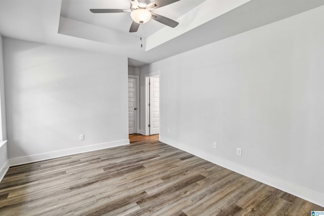 spare room with a raised ceiling, hardwood / wood-style flooring, and ceiling fan