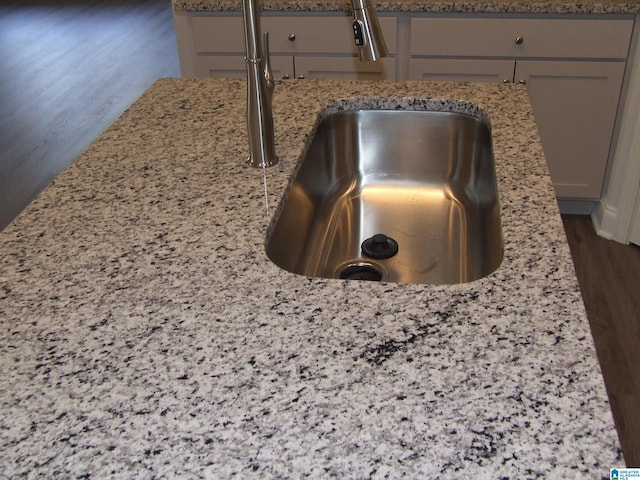 interior details featuring sink, light stone counters, and dark hardwood / wood-style floors