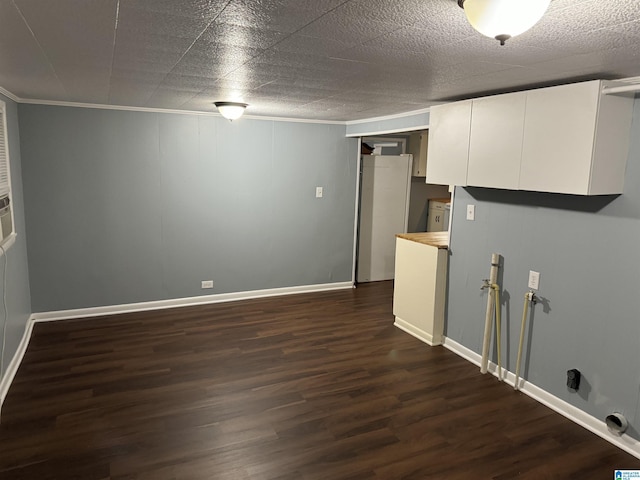 laundry area with crown molding, dark wood-type flooring, and cabinets