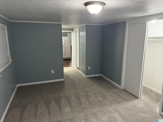 unfurnished bedroom with crown molding, white refrigerator with ice dispenser, carpet, and a textured ceiling