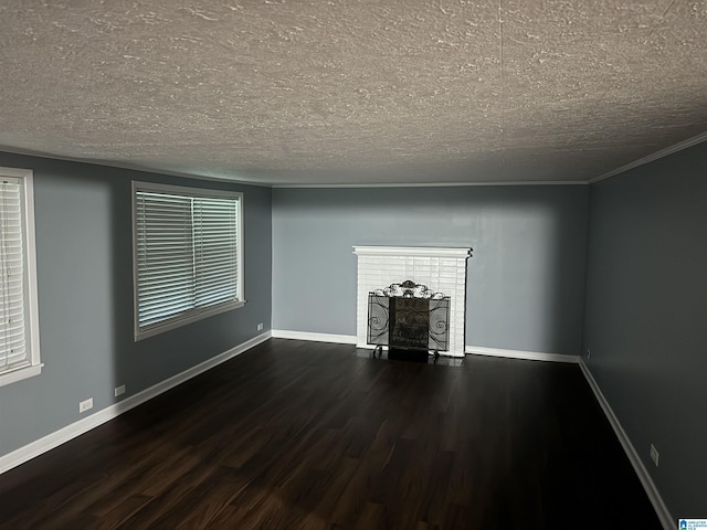 unfurnished living room with crown molding, dark wood-type flooring, a fireplace, and a textured ceiling