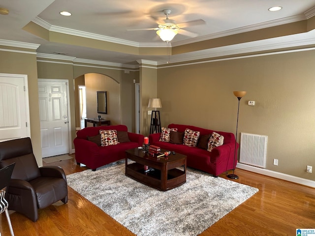 living room featuring crown molding, ceiling fan, a tray ceiling, and hardwood / wood-style floors