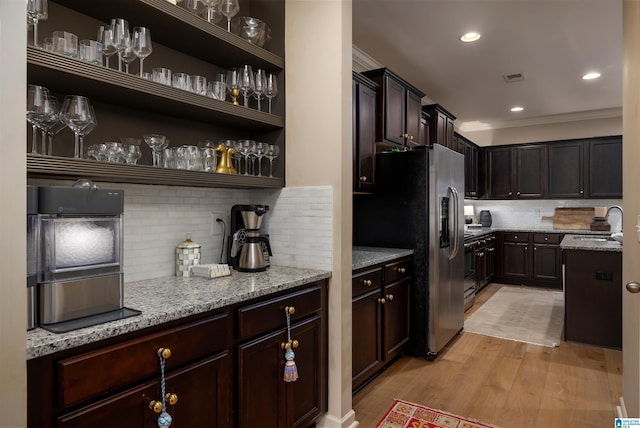 kitchen featuring tasteful backsplash, sink, light stone counters, light hardwood / wood-style floors, and stainless steel refrigerator with ice dispenser