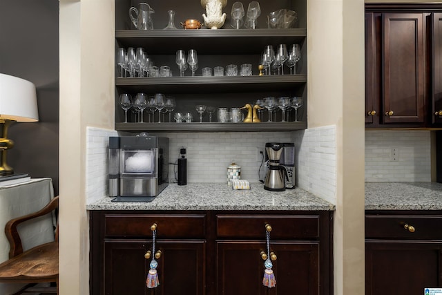 bar with tasteful backsplash, dark brown cabinetry, and light stone counters