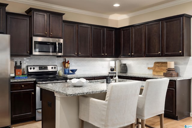 kitchen with stainless steel appliances, a breakfast bar, an island with sink, and backsplash