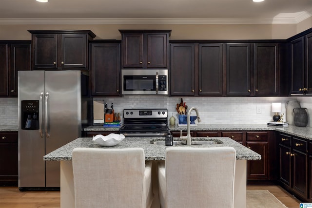 kitchen with tasteful backsplash, sink, an island with sink, and appliances with stainless steel finishes