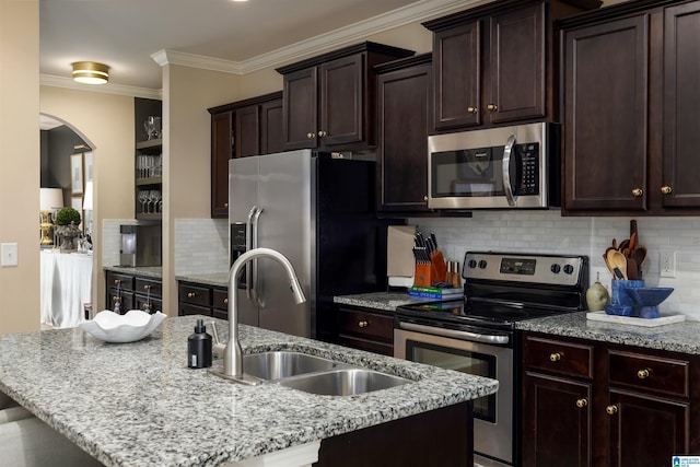 kitchen featuring stainless steel appliances, an island with sink, sink, and decorative backsplash