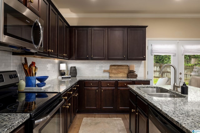 kitchen featuring sink, backsplash, dark brown cabinets, stainless steel appliances, and light stone countertops