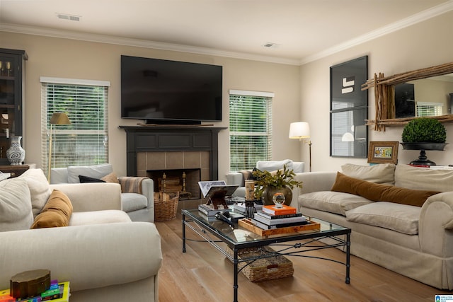 living room with ornamental molding, light hardwood / wood-style floors, and a tile fireplace