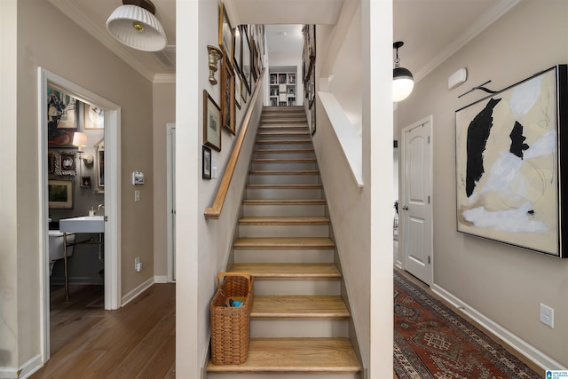 staircase with ornamental molding and hardwood / wood-style floors